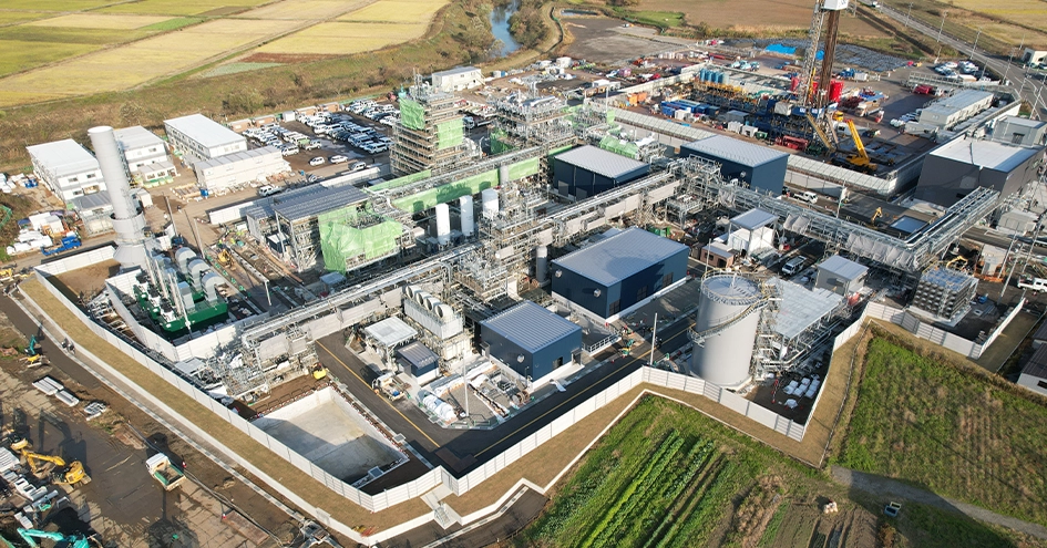 さまざまな構造を持つ産業施設と、建設中の水素・アンモニア製造・利用実証の建物。
