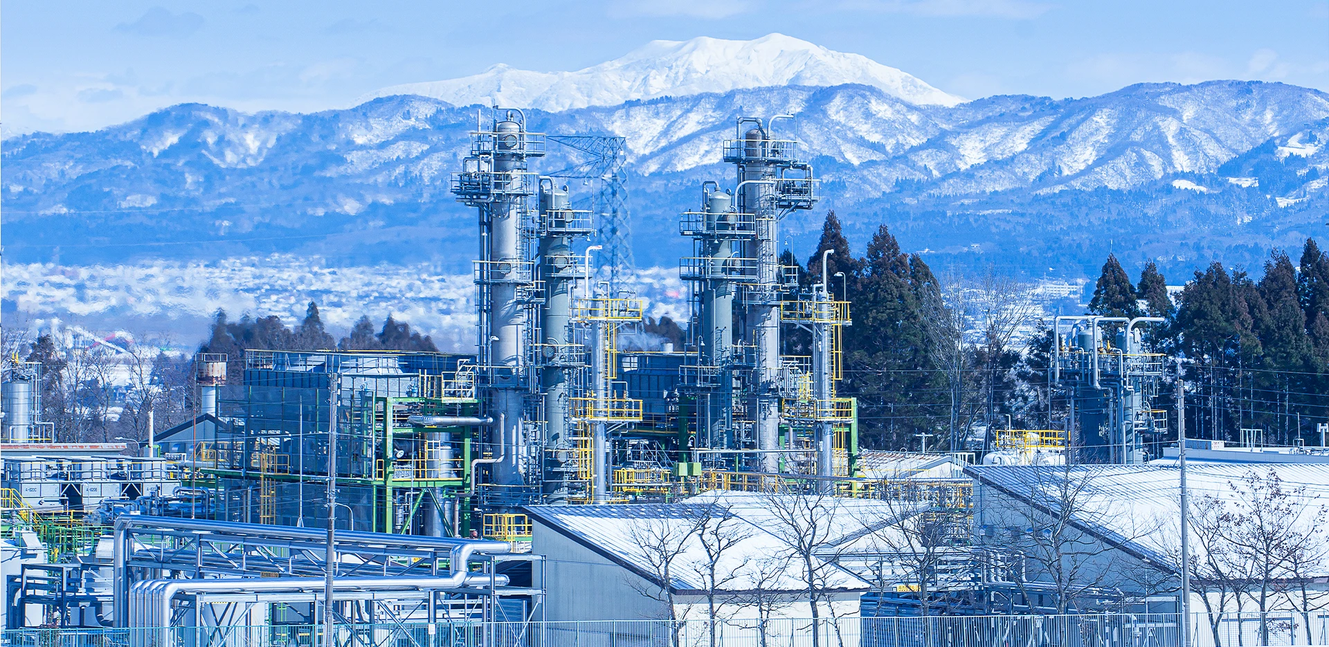 雪景色の中にある石油天然ガス施設で、背景には山々が広がる